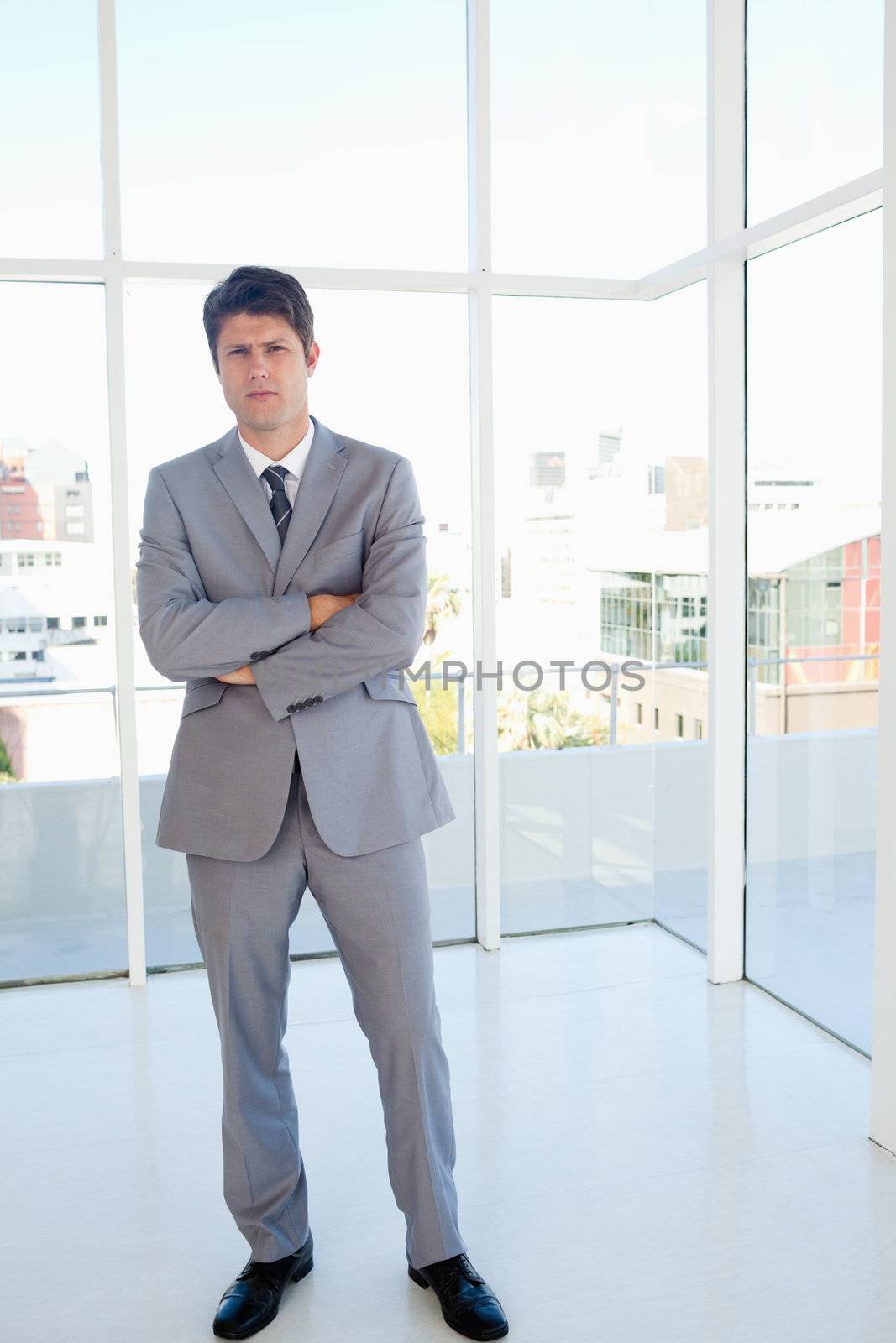 Serious businessman standing in a bright space