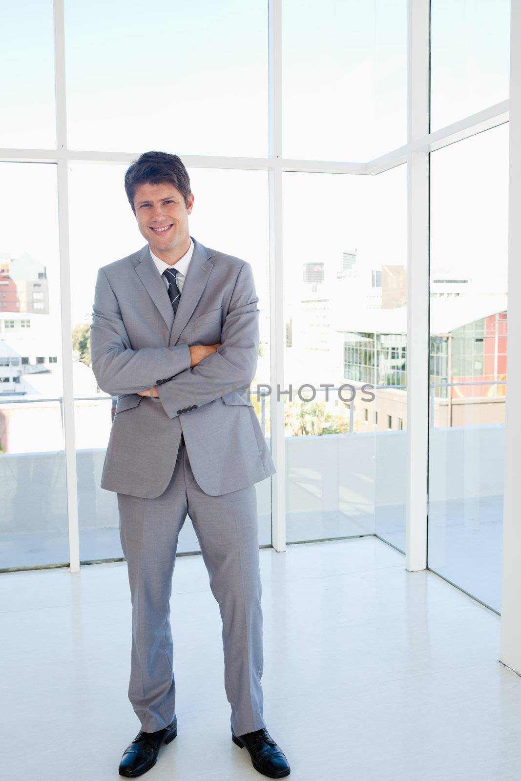 Happy businessman crossing his arms and standing with a view of the city behind him