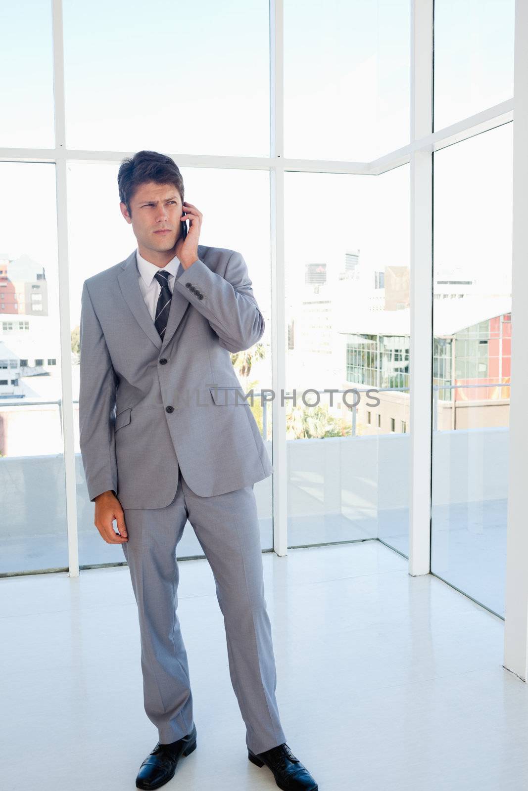 Strict businessman talking on a phone in a spacious room
