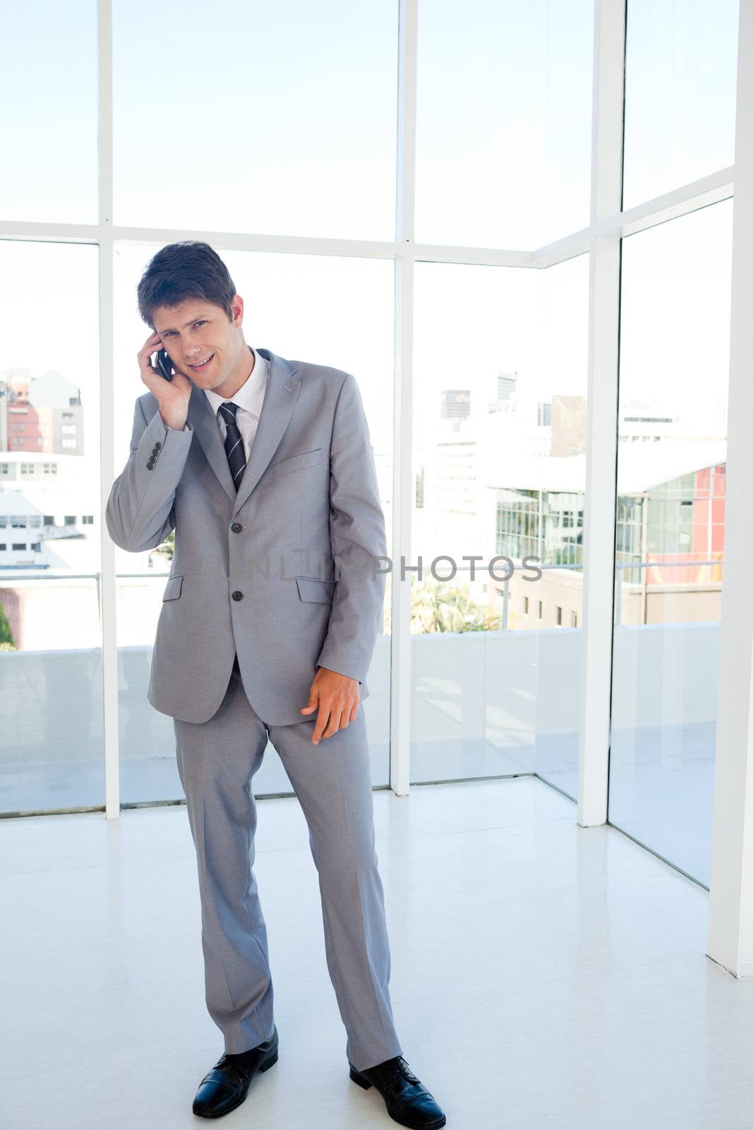 Smiling businessman making a call while leaning his head to the  by Wavebreakmedia