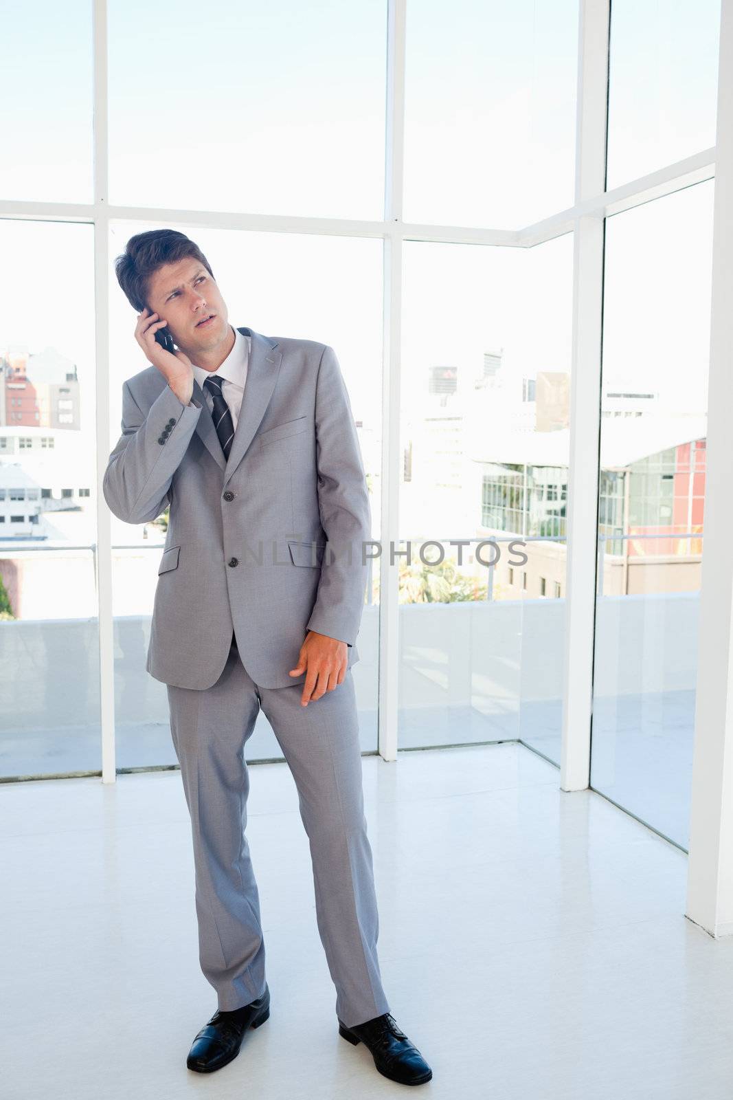 Businessman making a call while looking upwards  by Wavebreakmedia