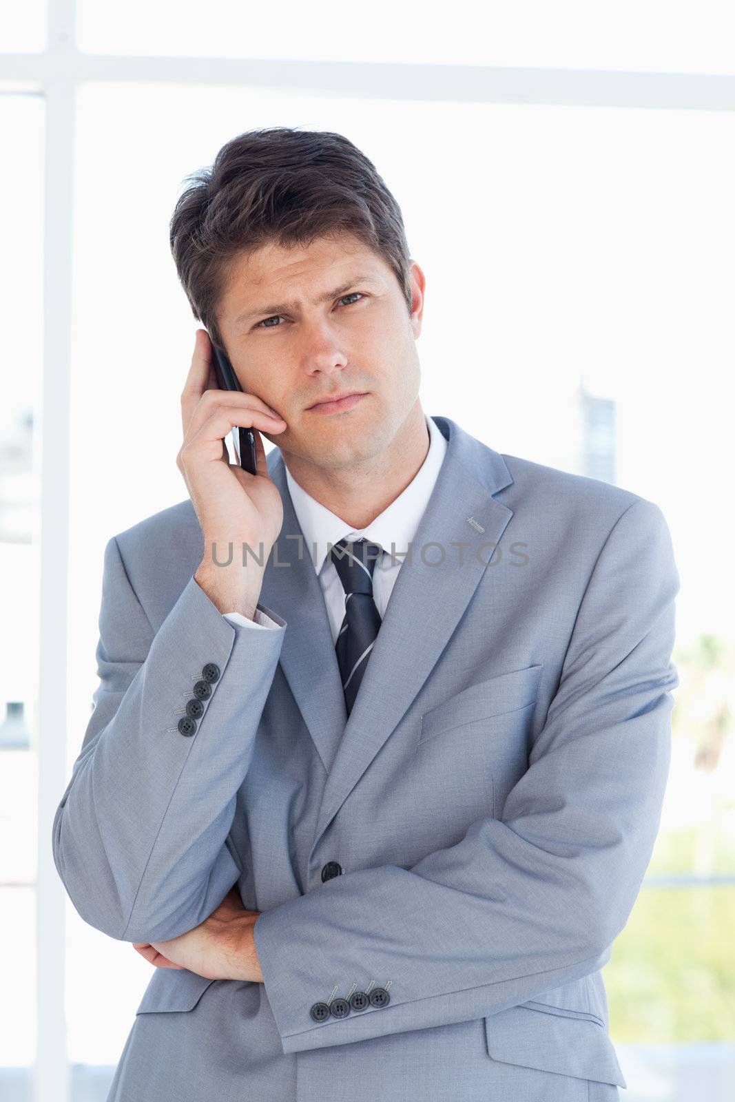 Serious businessman making a call while looking at the camera by Wavebreakmedia