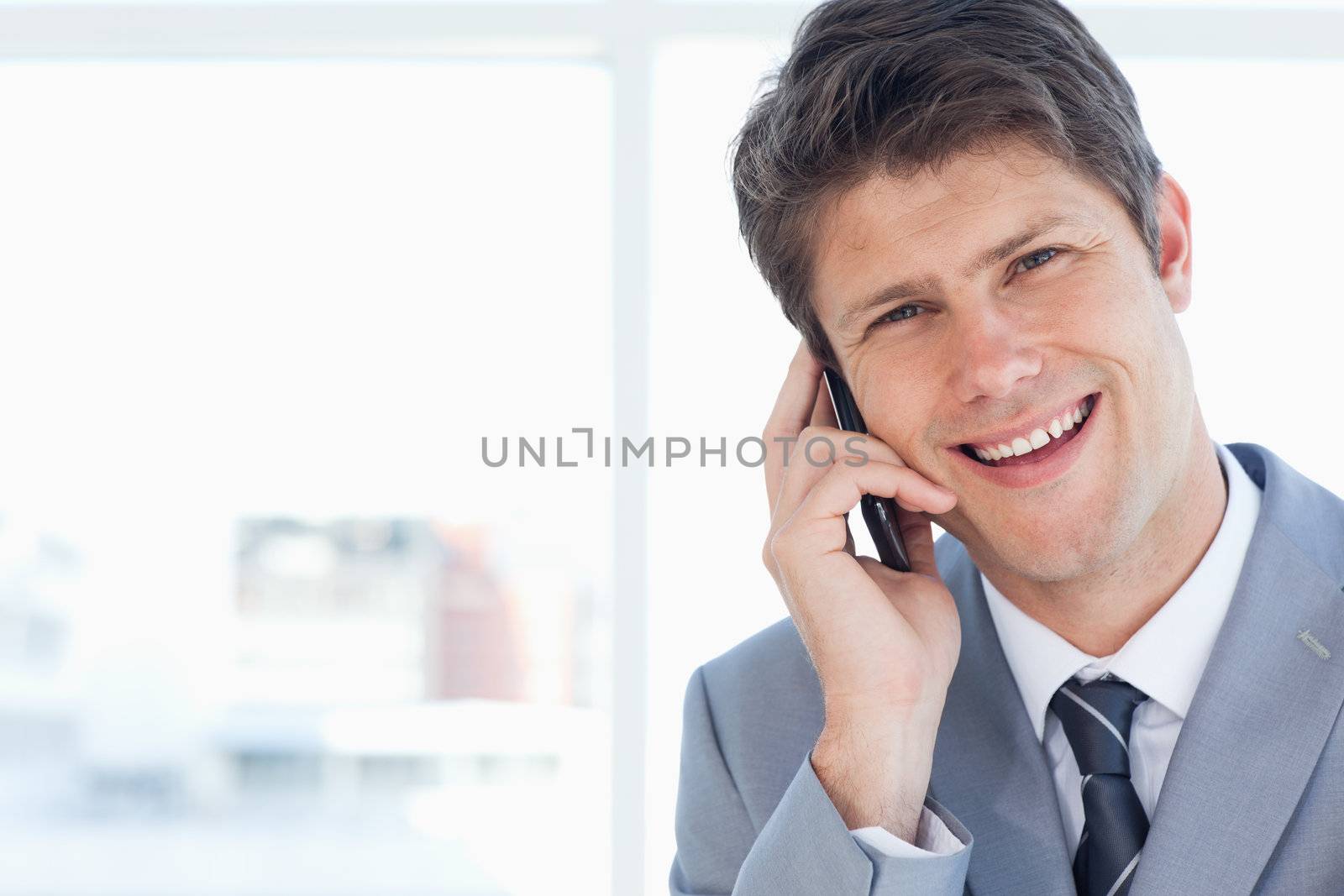 Young businessman laughing while talking on the phone by Wavebreakmedia
