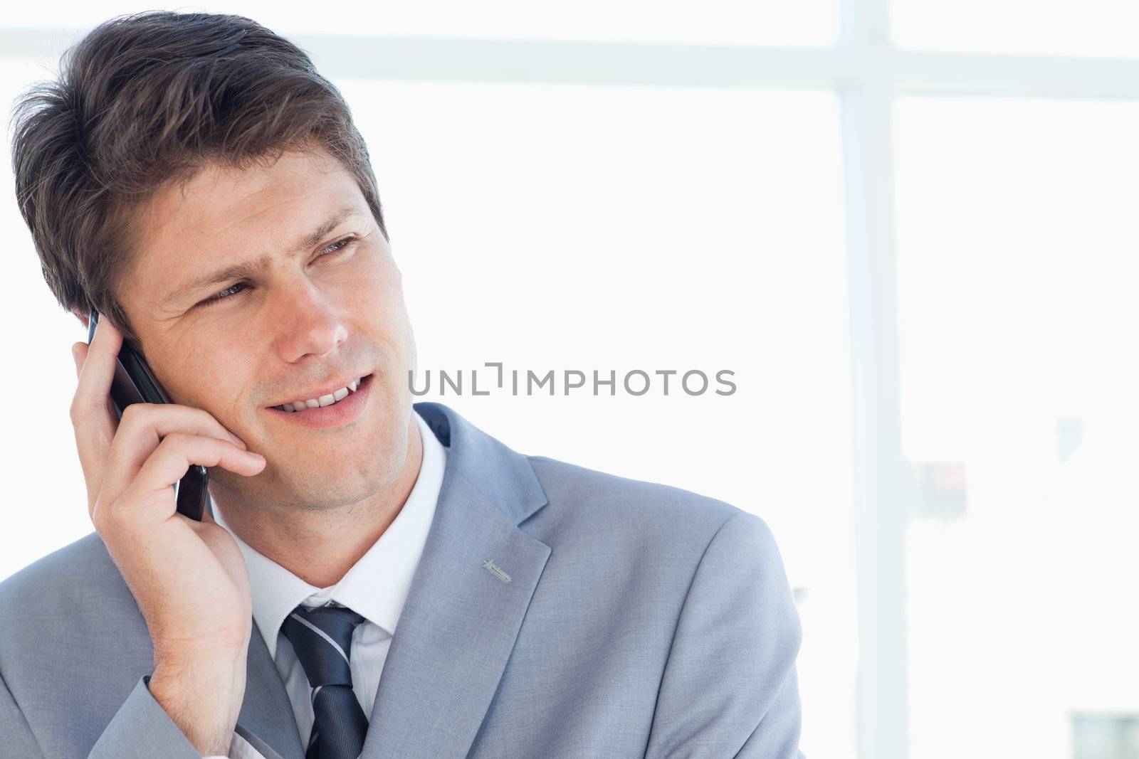 Stern businessman talking on the phone while looking towards the by Wavebreakmedia