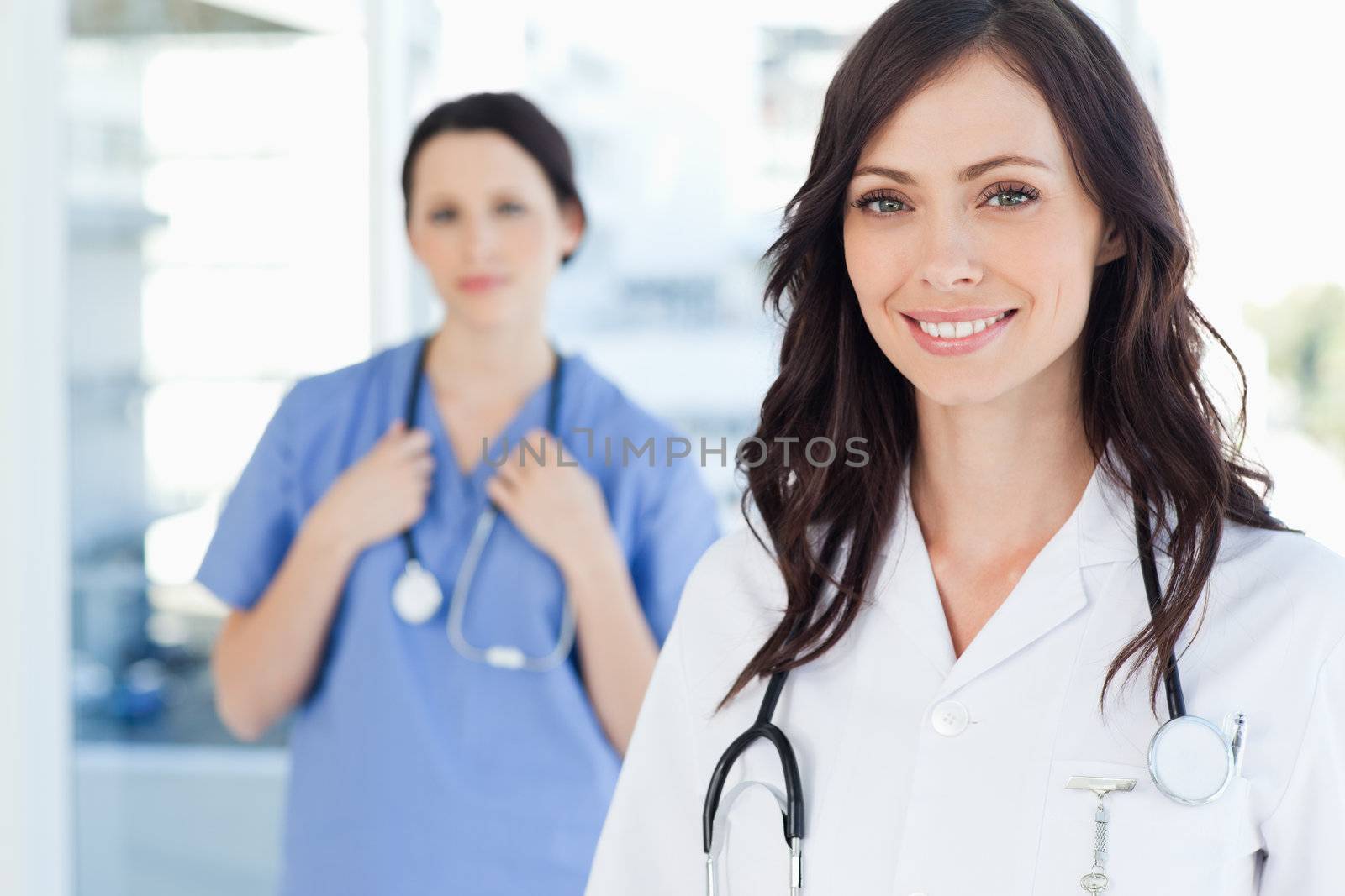 Young smiling nurse accompanied by a co-worker in the background