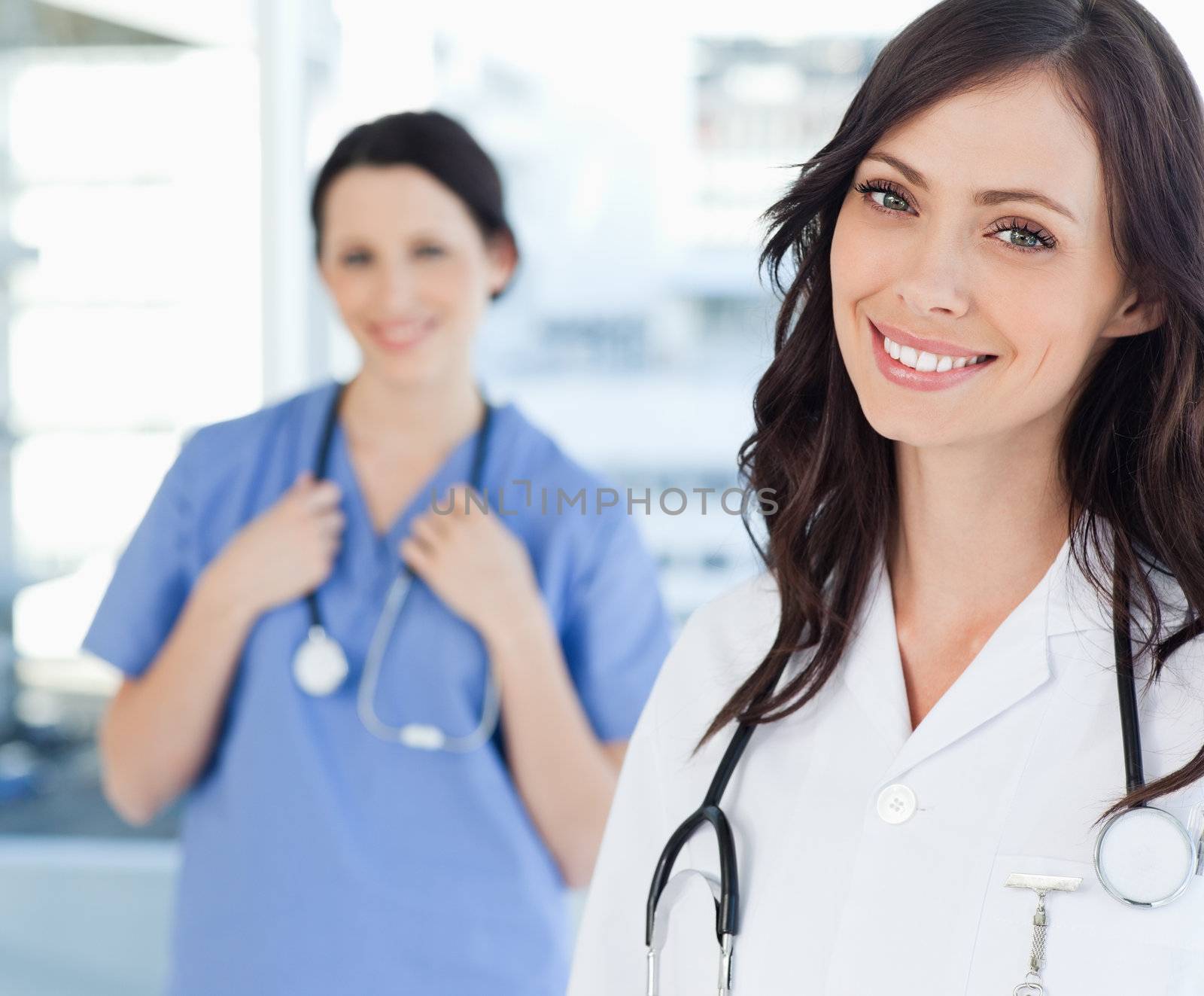 Smiling nurse standing upright while leaning her head to the sid by Wavebreakmedia
