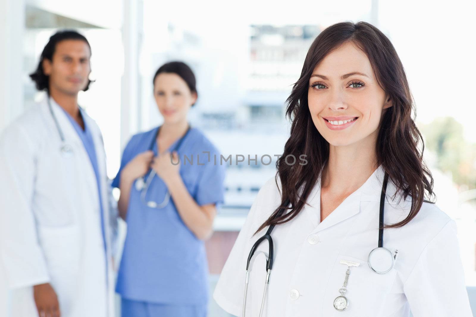 Smiling nurse standing in front of two co-workers