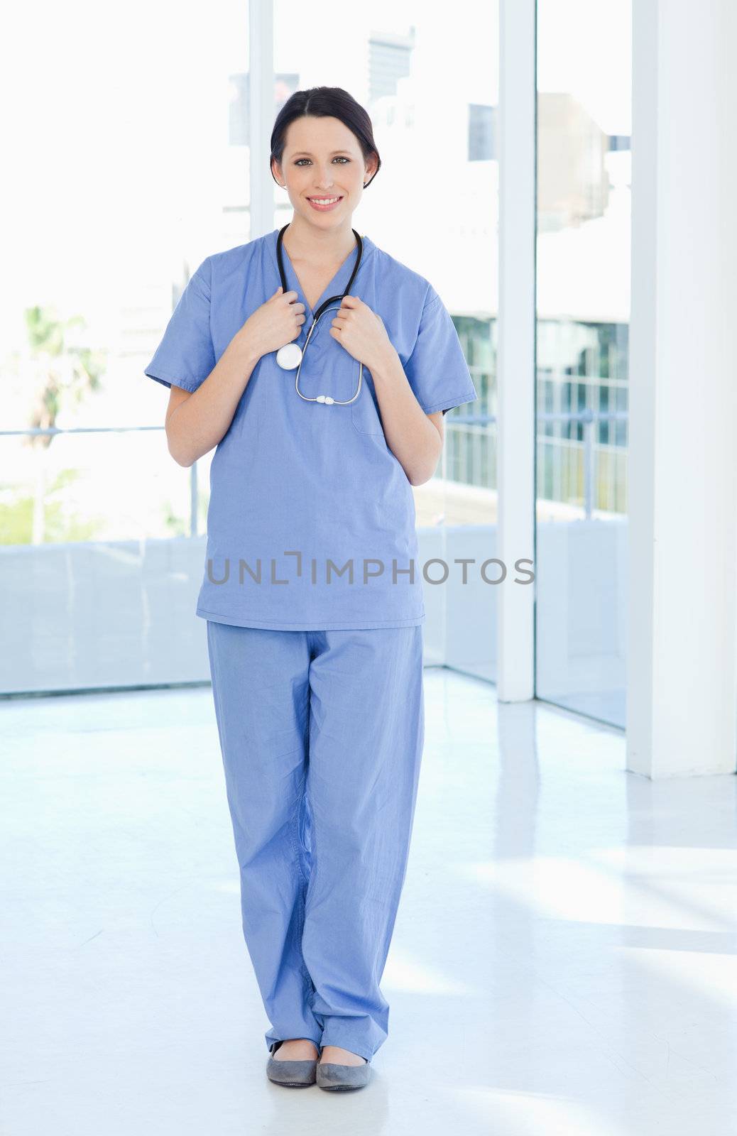 Smiling medical intern wearing a blue short-sleeve uniform by Wavebreakmedia