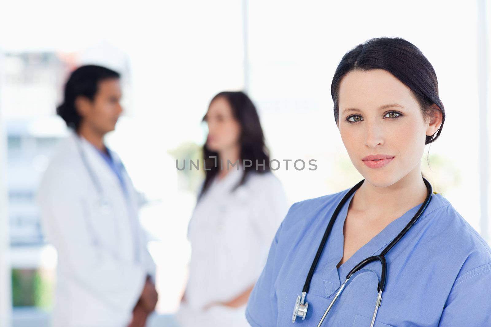Young nurse calmly standing upright with her stethoscope around her neck