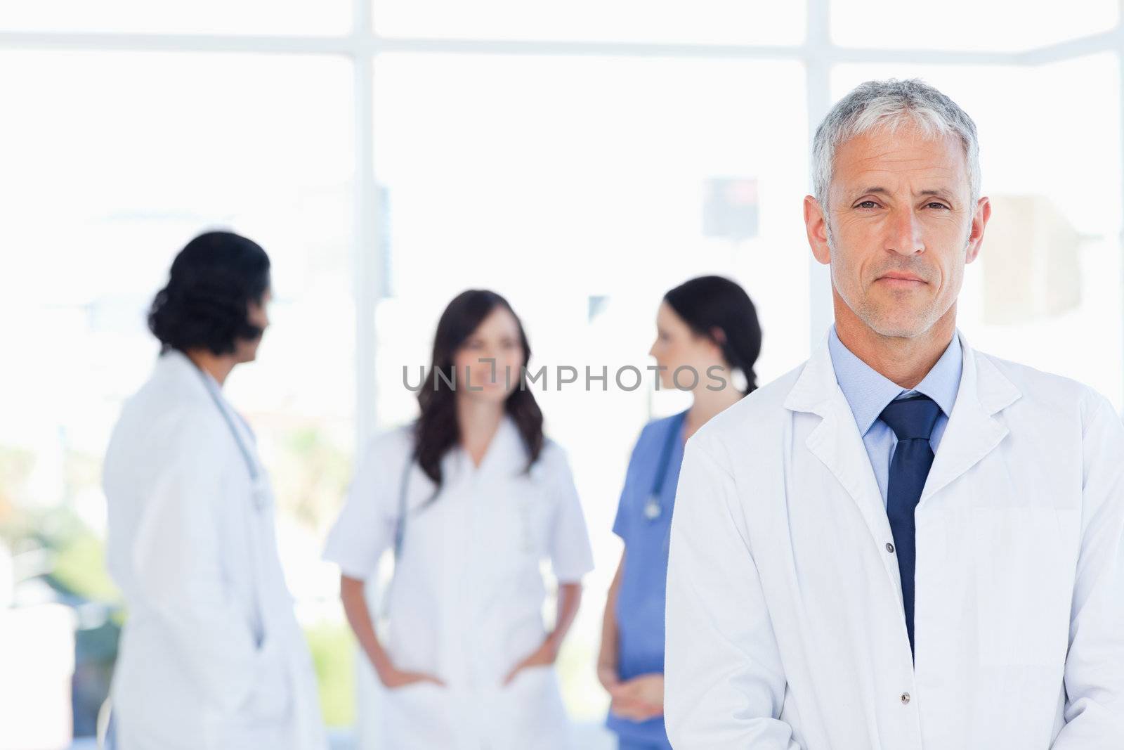 Serous doctor standing in the foreground and accompanied by his team