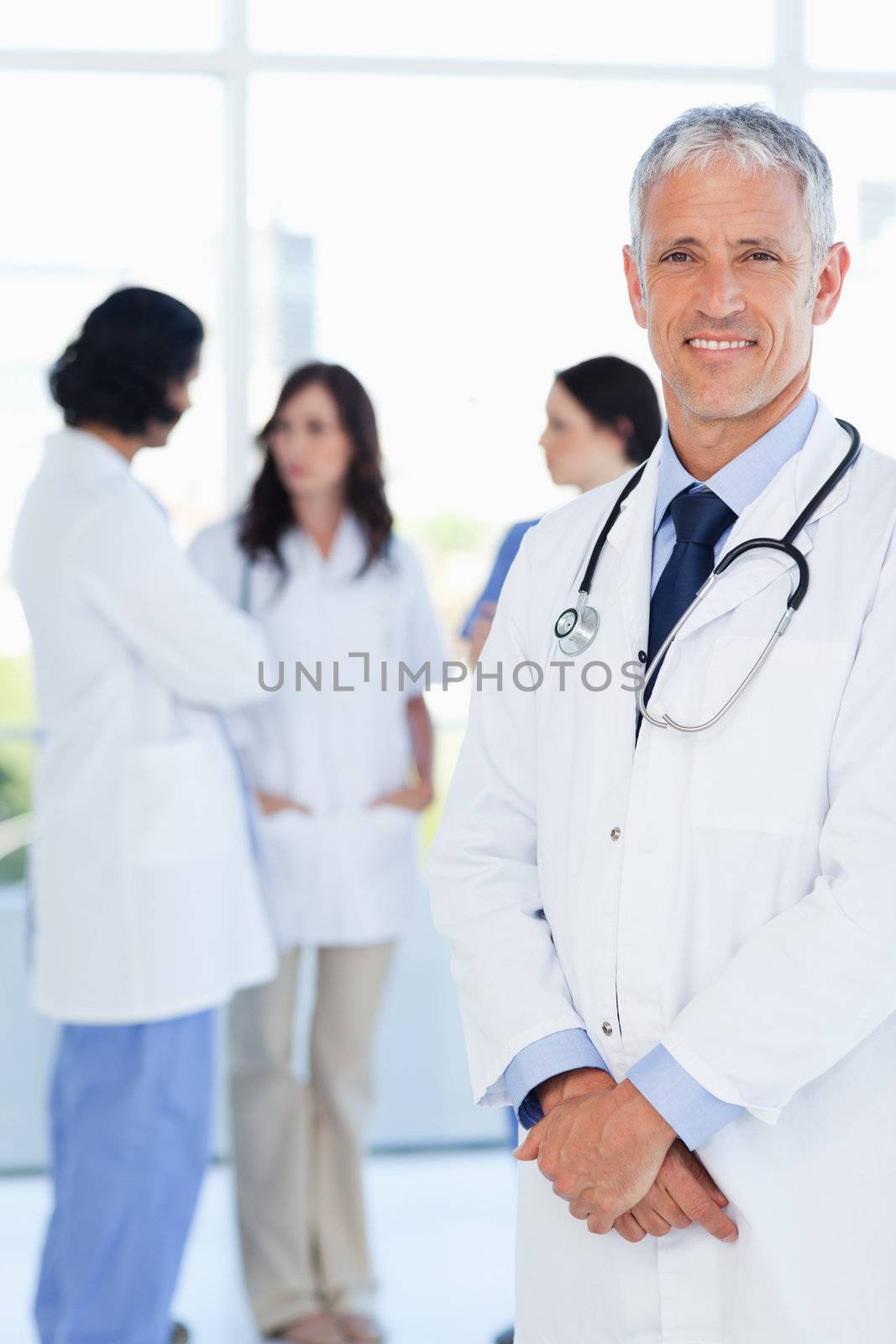 Mature doctor crossing his hands in front of his team by Wavebreakmedia