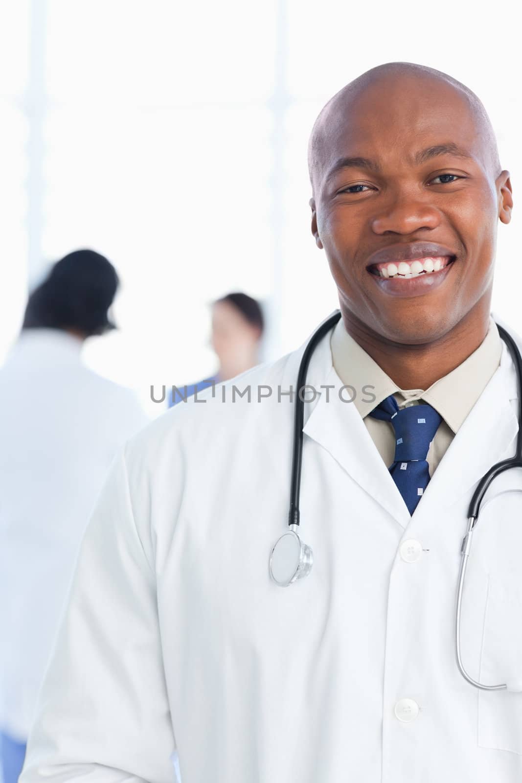 Medical intern showing a beaming smile in front of his team by Wavebreakmedia