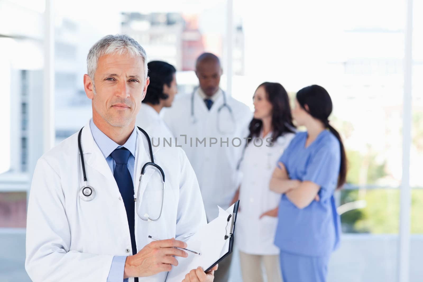 Mature doctor pointing seriously at something on his clipboard