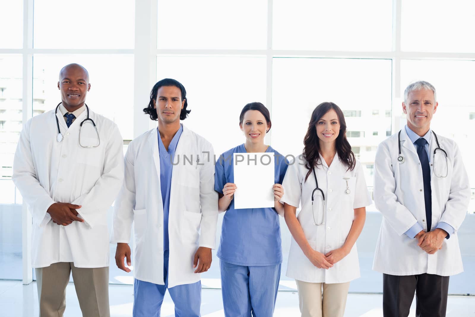 Medical people surrounding a new intern which is holding a blank sheet