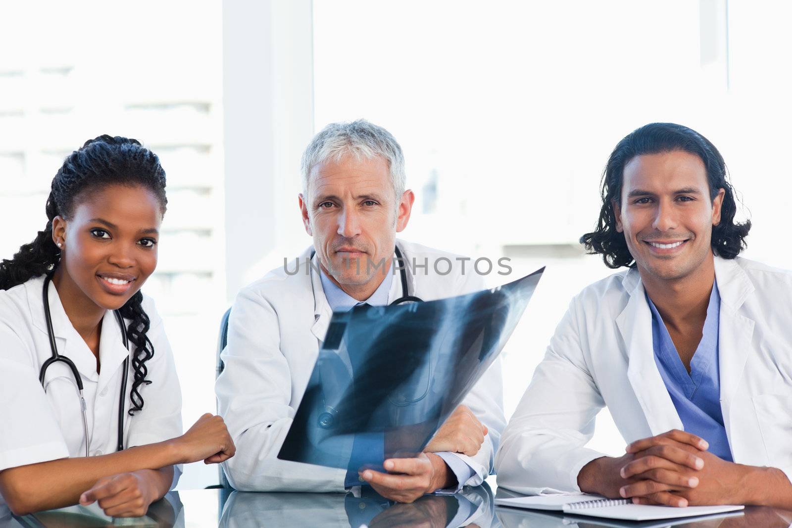 Mature doctor with smiling colleagues looking at an x-ray scan of lungs