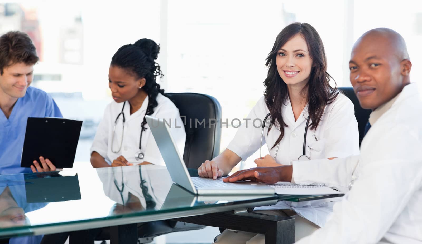 Members of a medical tean looking at the camera while working on a laptop
