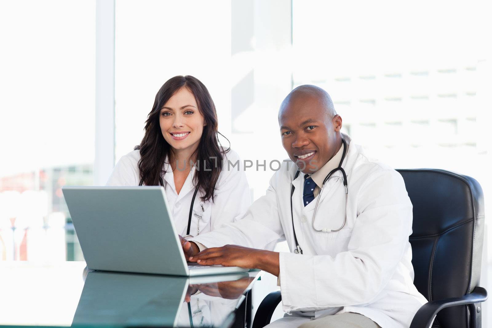 Smiling nurses seriously working while sitting at the desk in a bright room