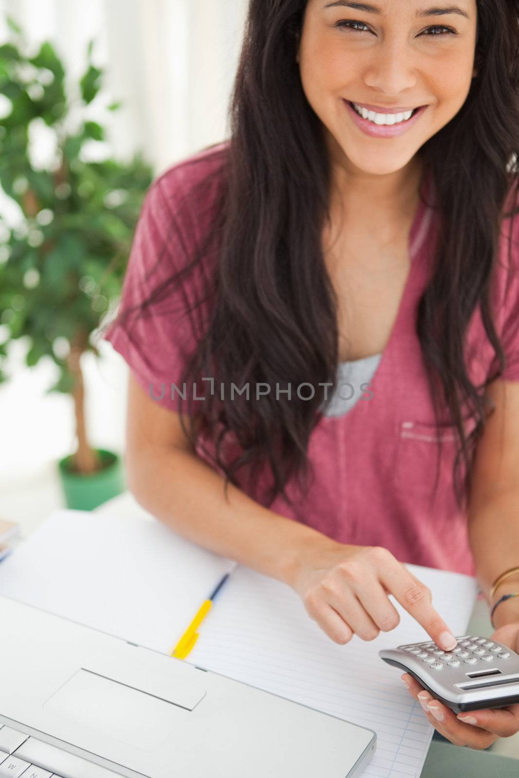 Portrait of a brunette student using a calculator by Wavebreakmedia