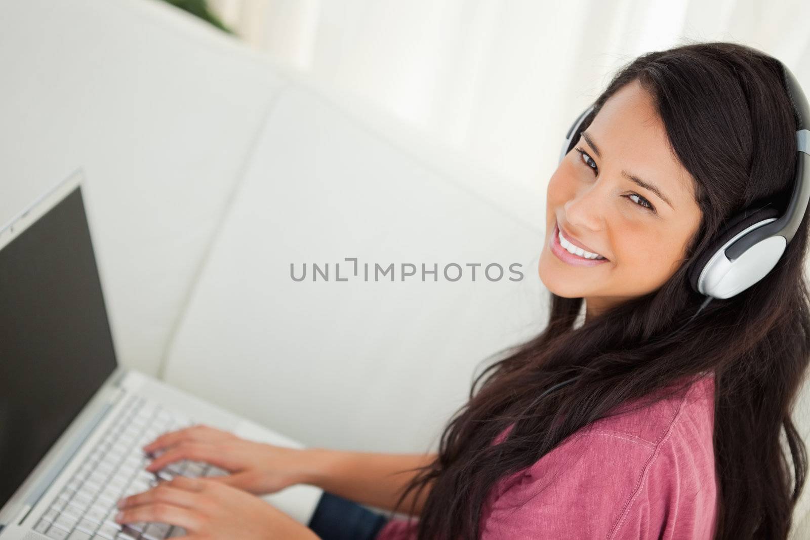High-angle view of a smiling student using her laptop on the sofa