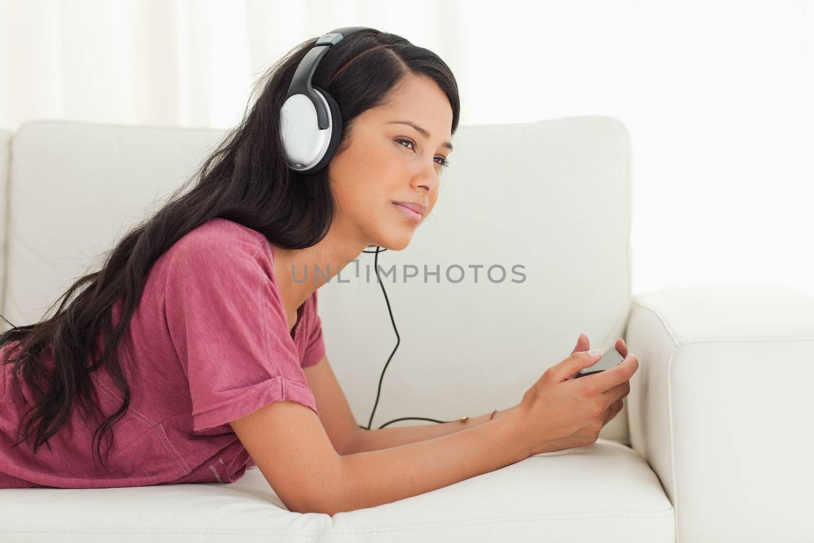 Young Latino listening music with a blank stare  by Wavebreakmedia