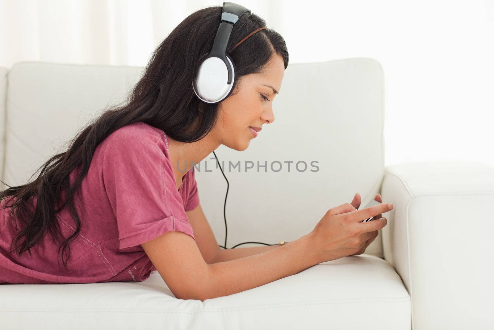 Young Latino frowning while listening to music on a sofa