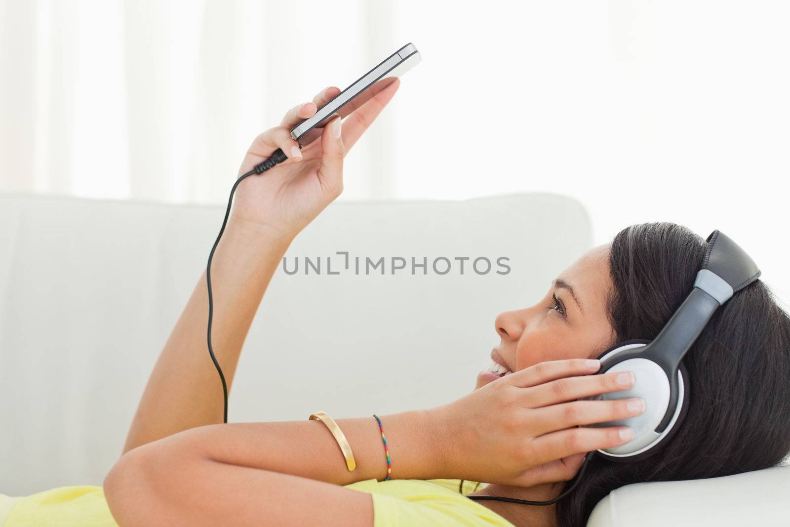 Portrait of a young Latino watching video on a smartphone while lying on a sofa