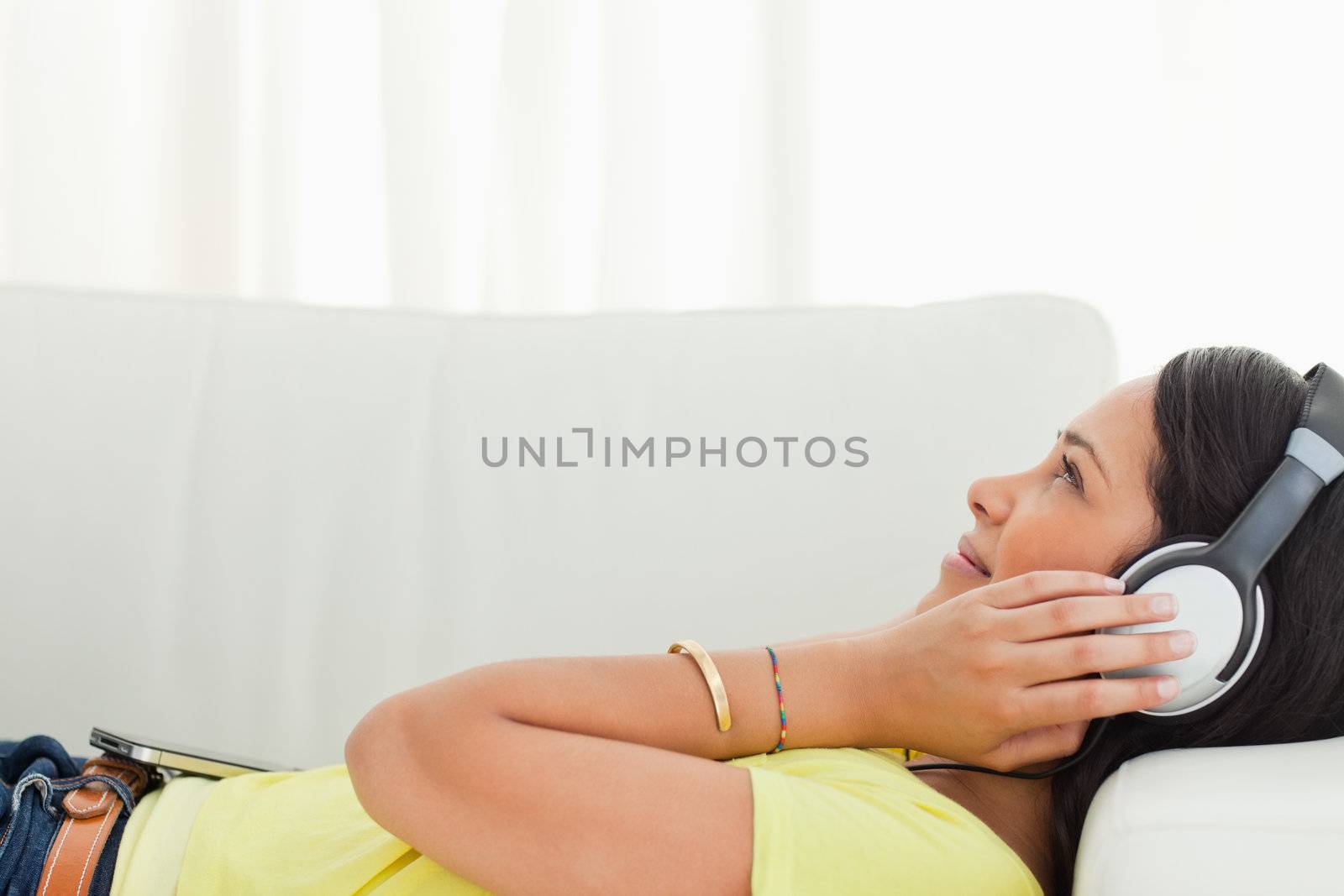 Young Latino listening music with a smartphone while lying on a sofa