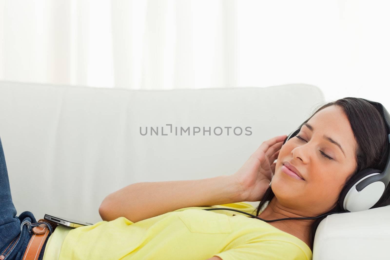 Young Latino enjoying music on a smartphone while lying on a sofa
