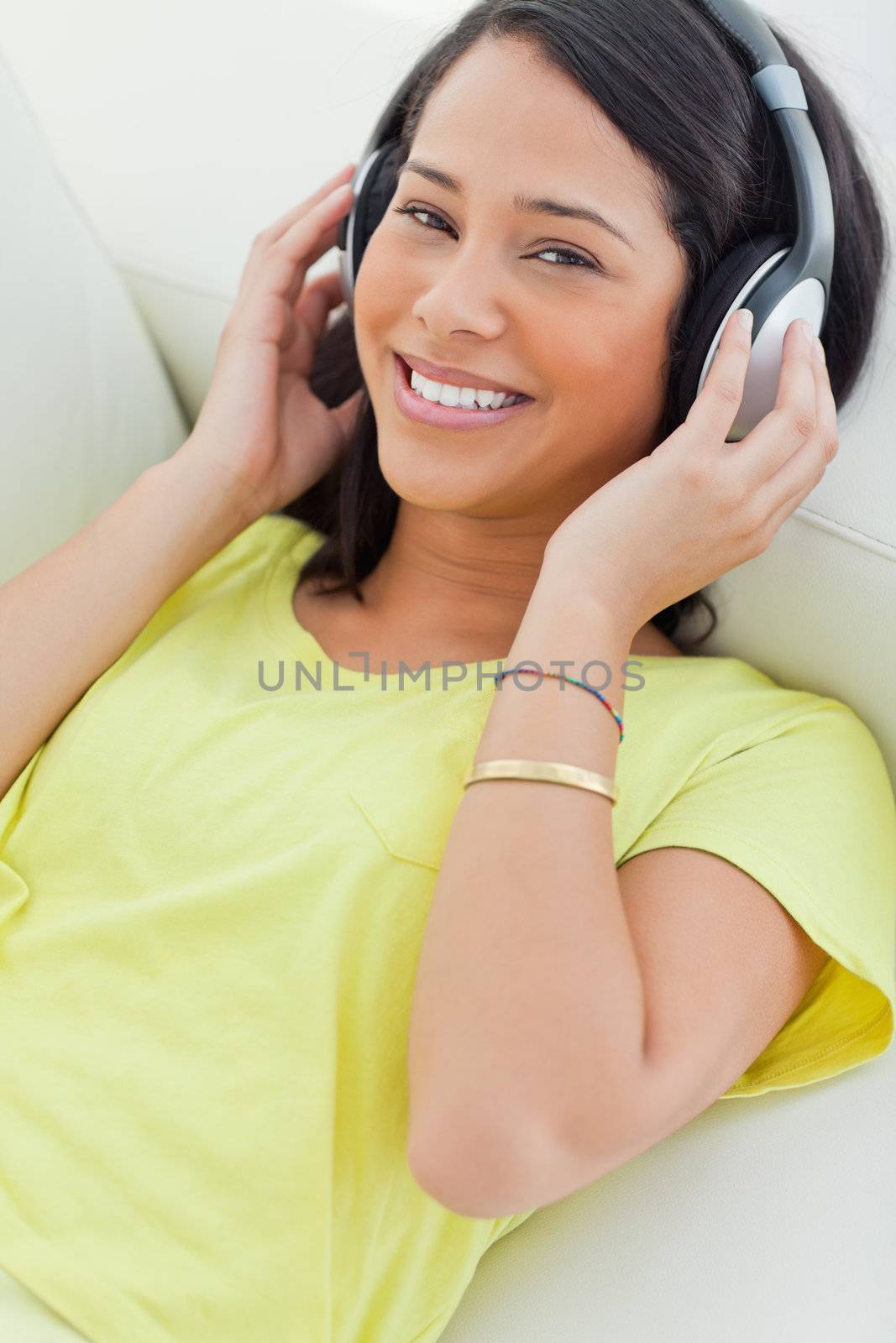 Portrait of a smiling Latino listening music on a smartphone by Wavebreakmedia
