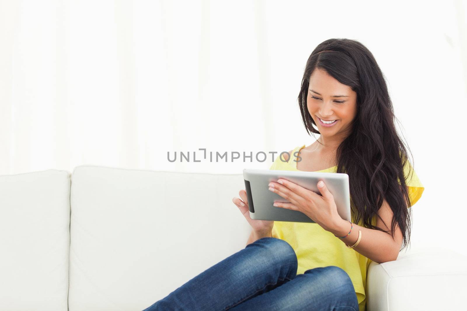 Beautiful smiling Latino using a touch pad on a sofa