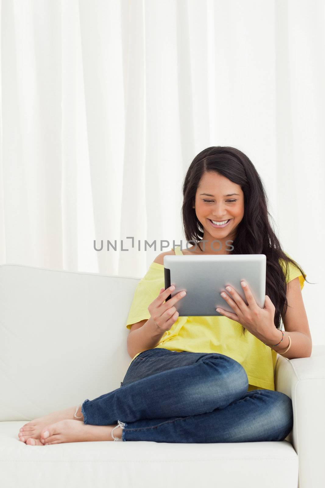 Beautiful smiling Latino looking a touch pad on a sofa