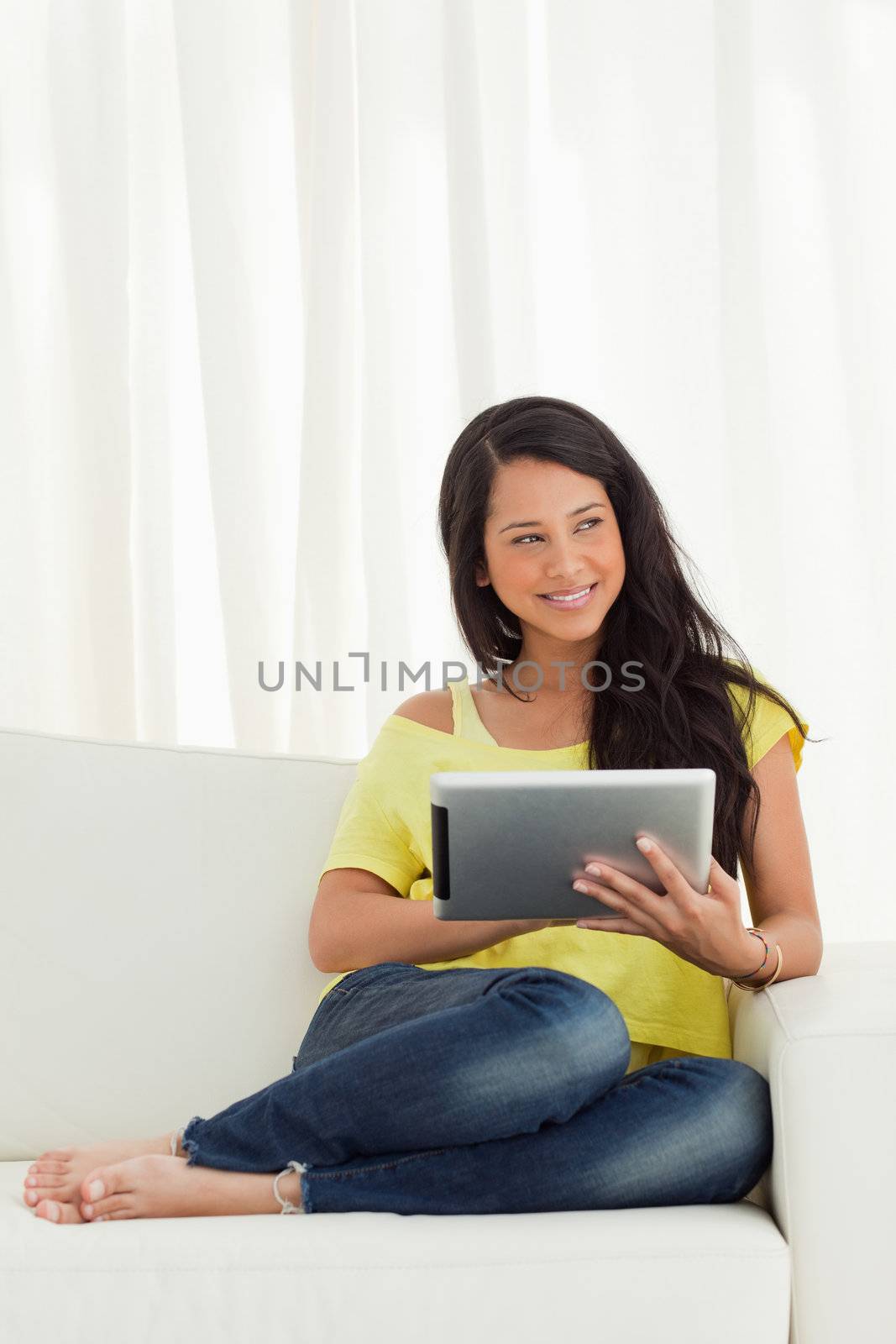 Beautiful Latino smiling while using a touch pad on a sofa