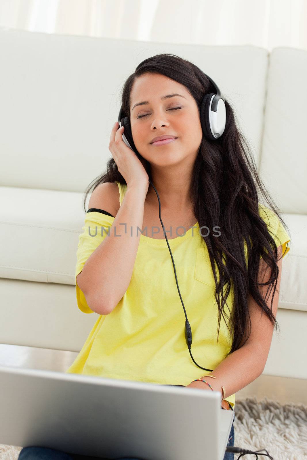 Close-up of a pretty Latin enjoying music on a laptop by Wavebreakmedia