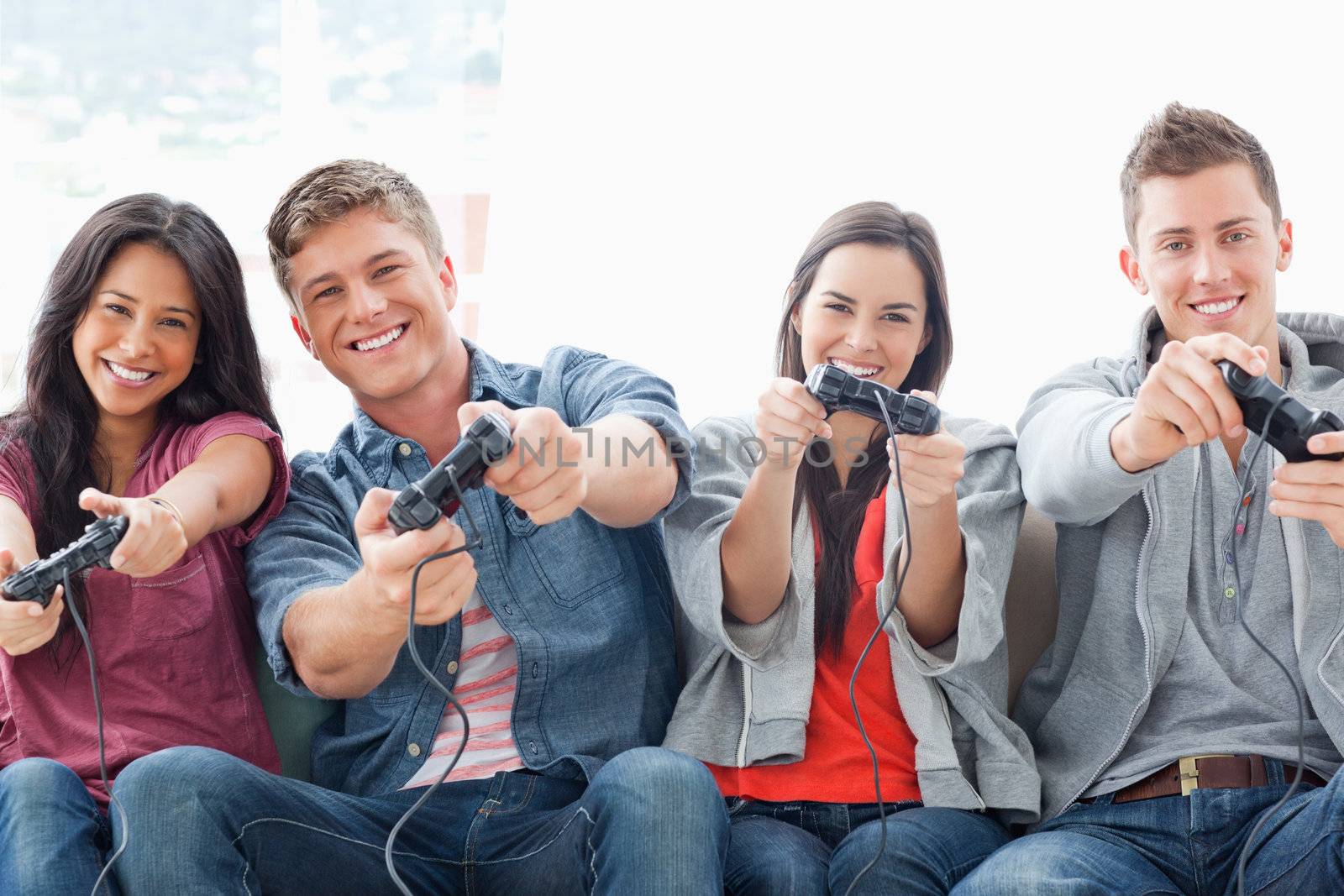 A happily smiling group of friends playing a game together while sitting on the couch