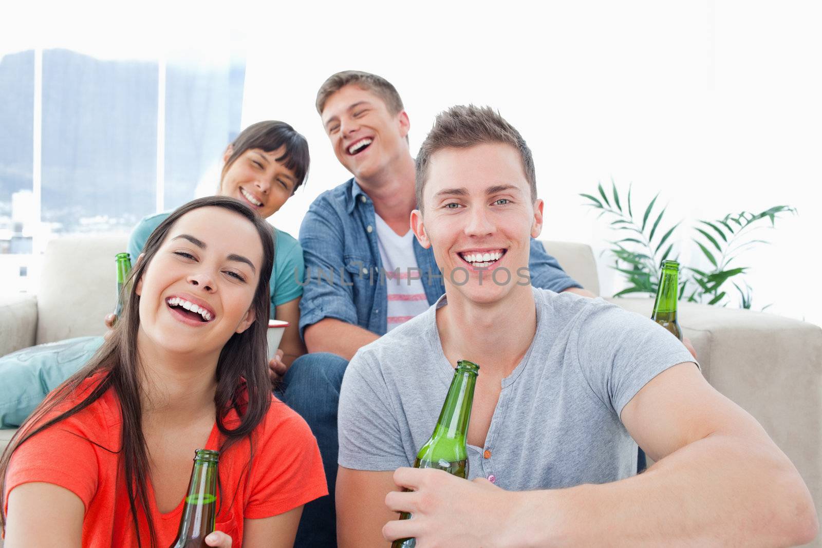 A laughing group inside the house enjoying beer and having fun together