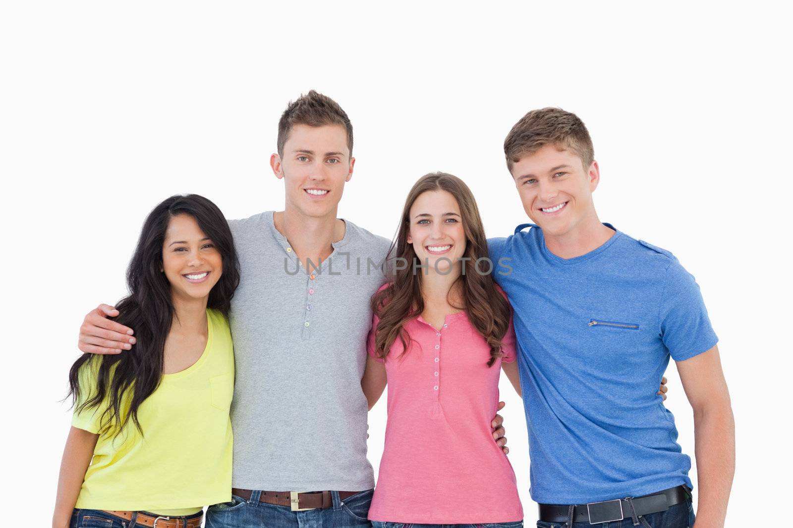 A group of friends standing beside and holding each other as they smile and look into the camera