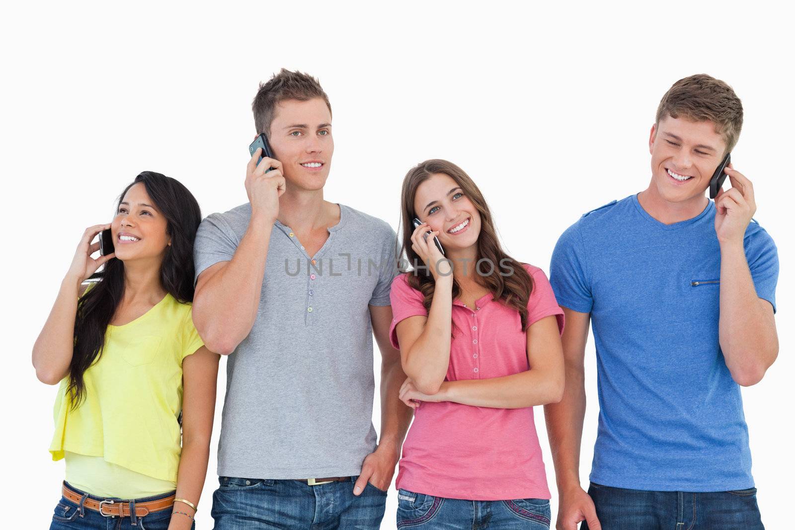 A group of friends on their phones making calls as they smile and stand beside each other 