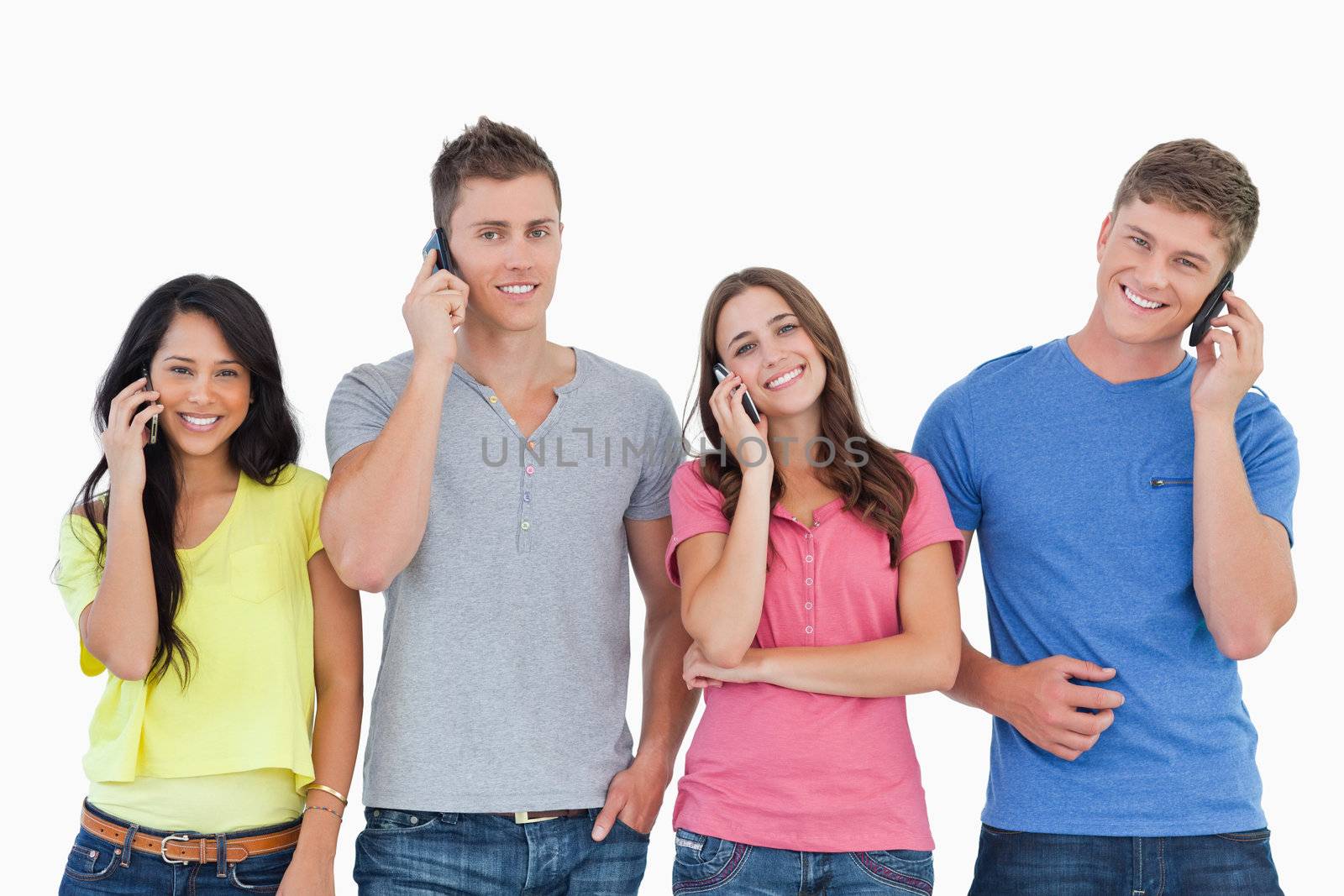 A group of friends of smiling as they all make calls and look into the camera 