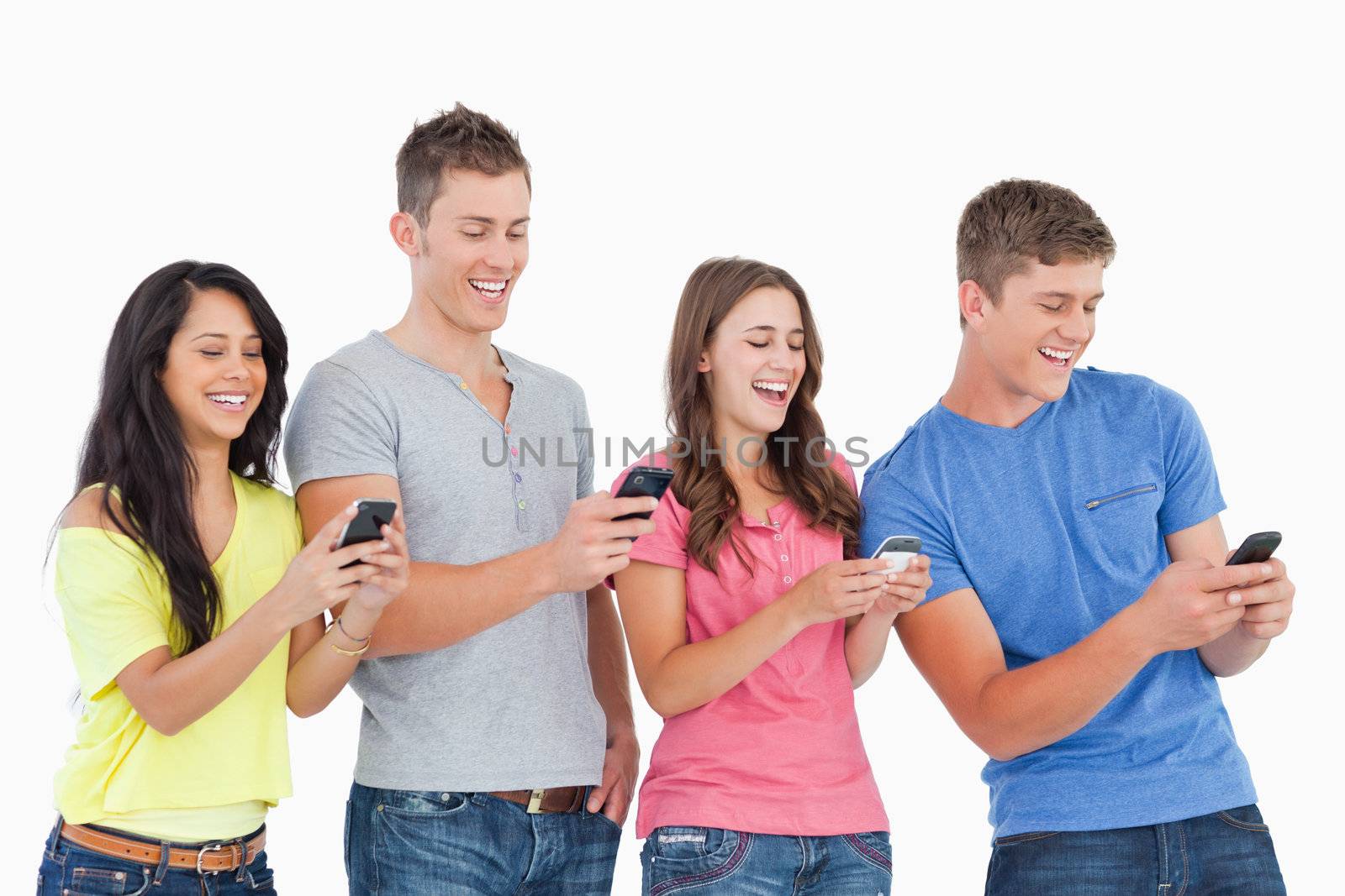 A group of friends laughing as they all send texts with their phones 