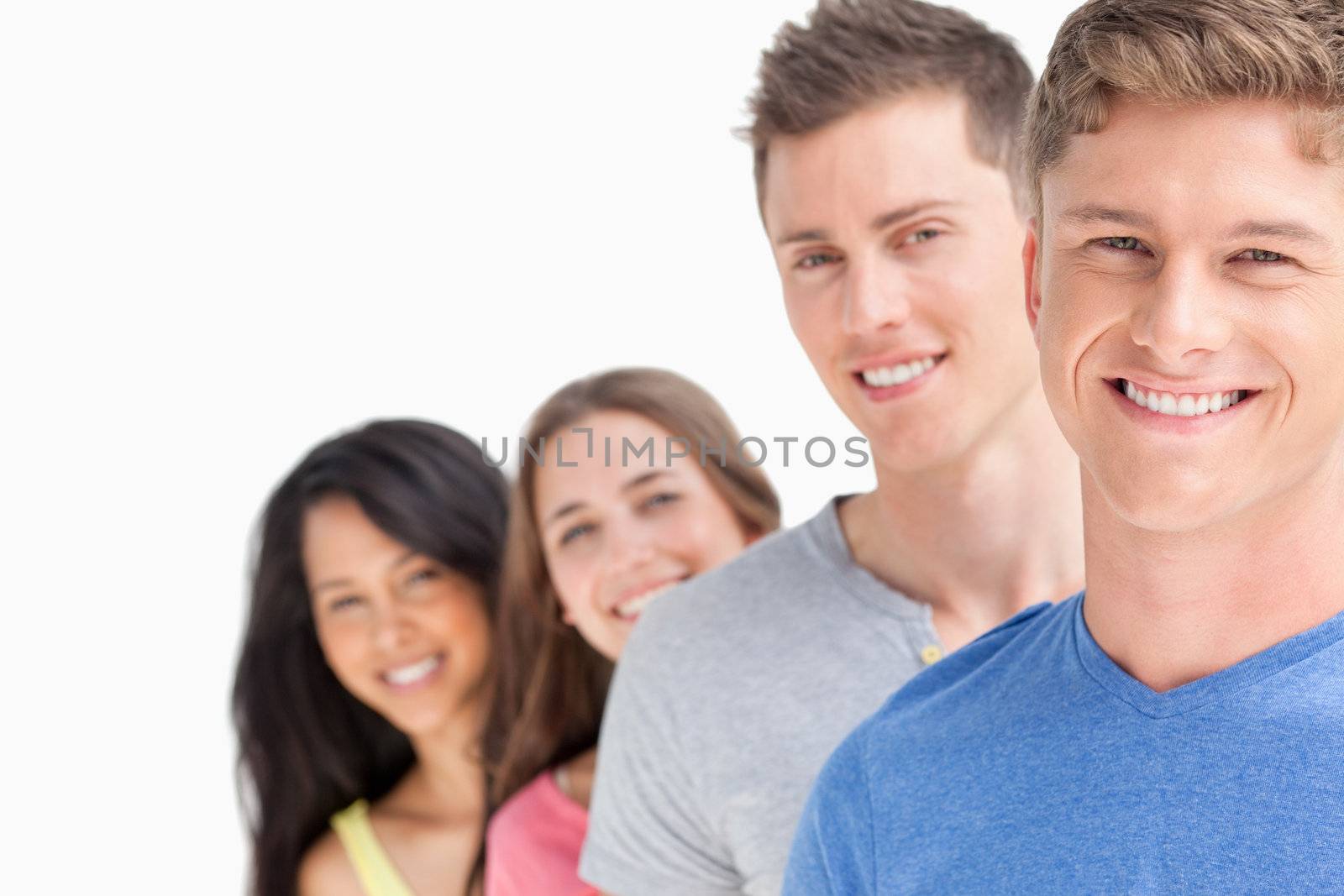 A group of people standing one in front of the other at a slight angle looking into the camera 