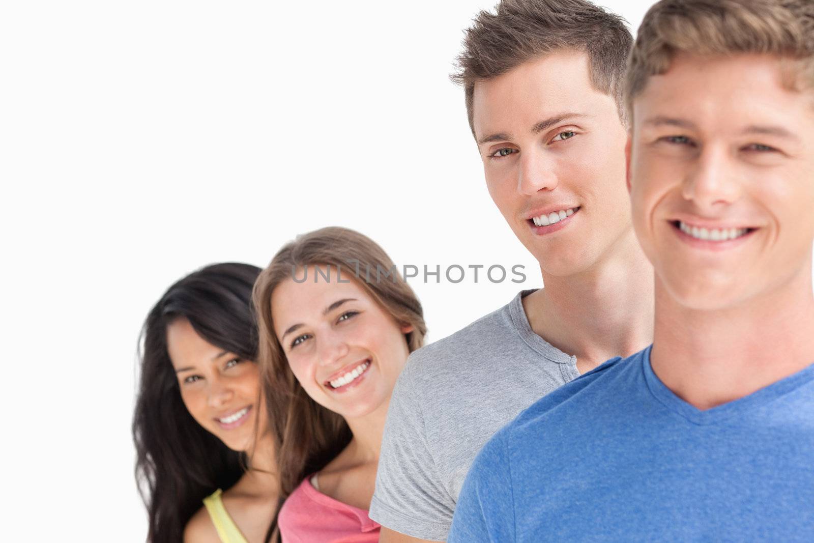 A group of four people standing one in front of the other with the girls heads out a little more as they all look at the camera 