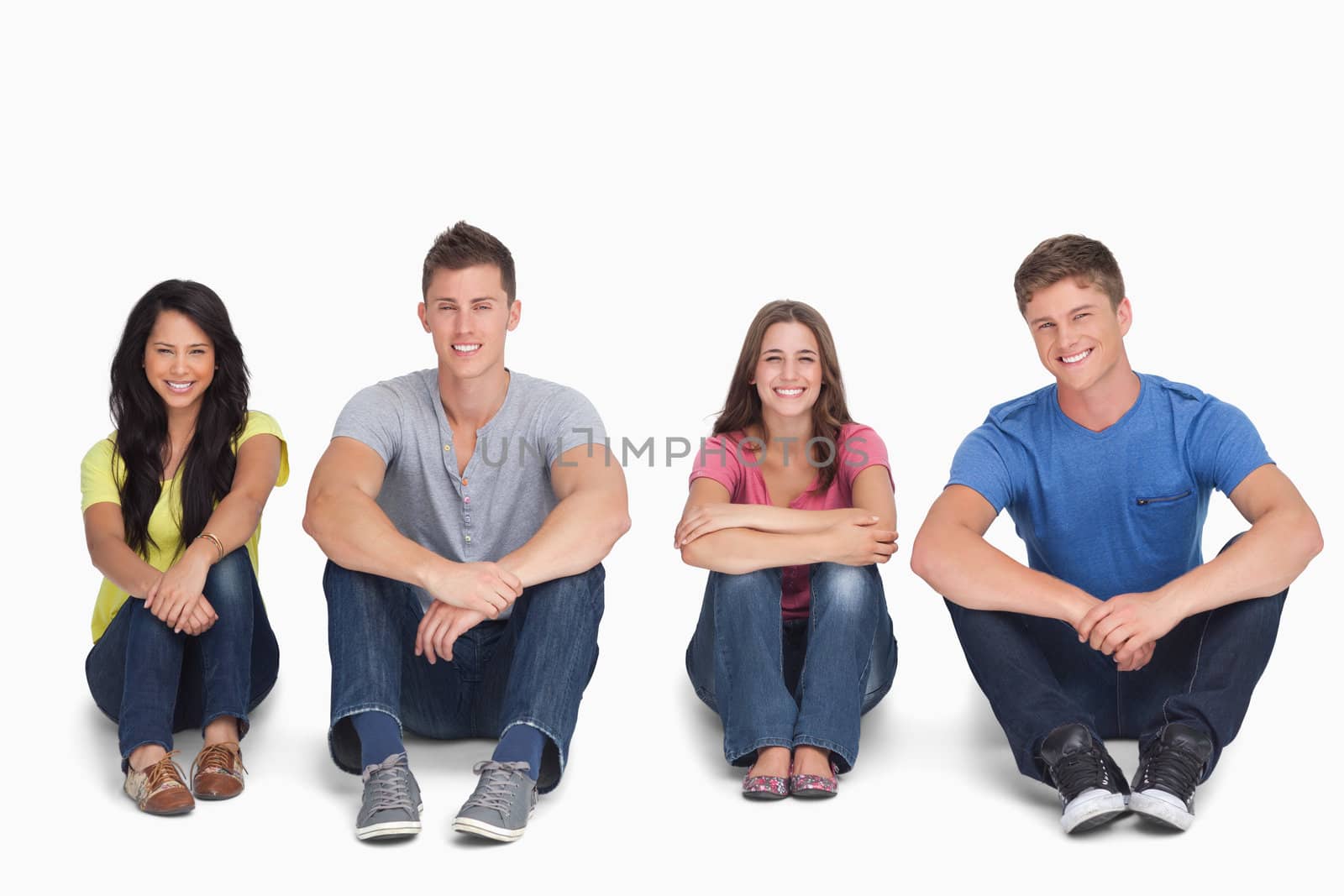 A smiling group looking at the camera with their knees up and their arms on them