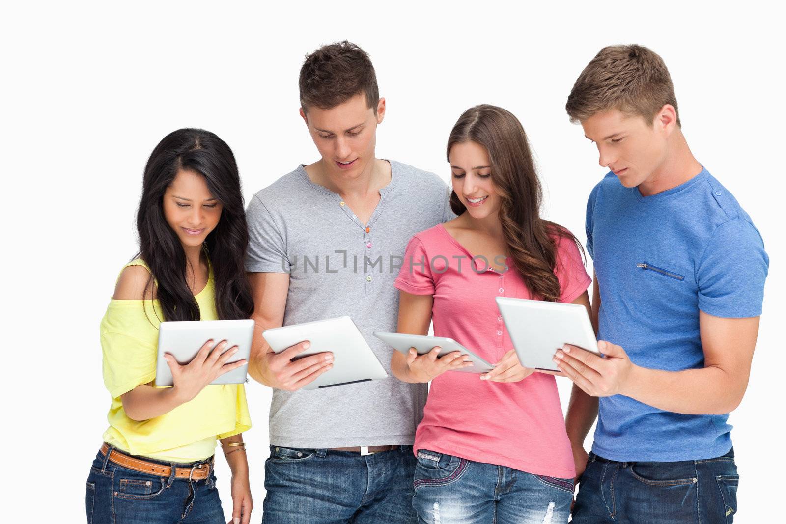 A group of friends looking at the screen of their tablets while beside each other