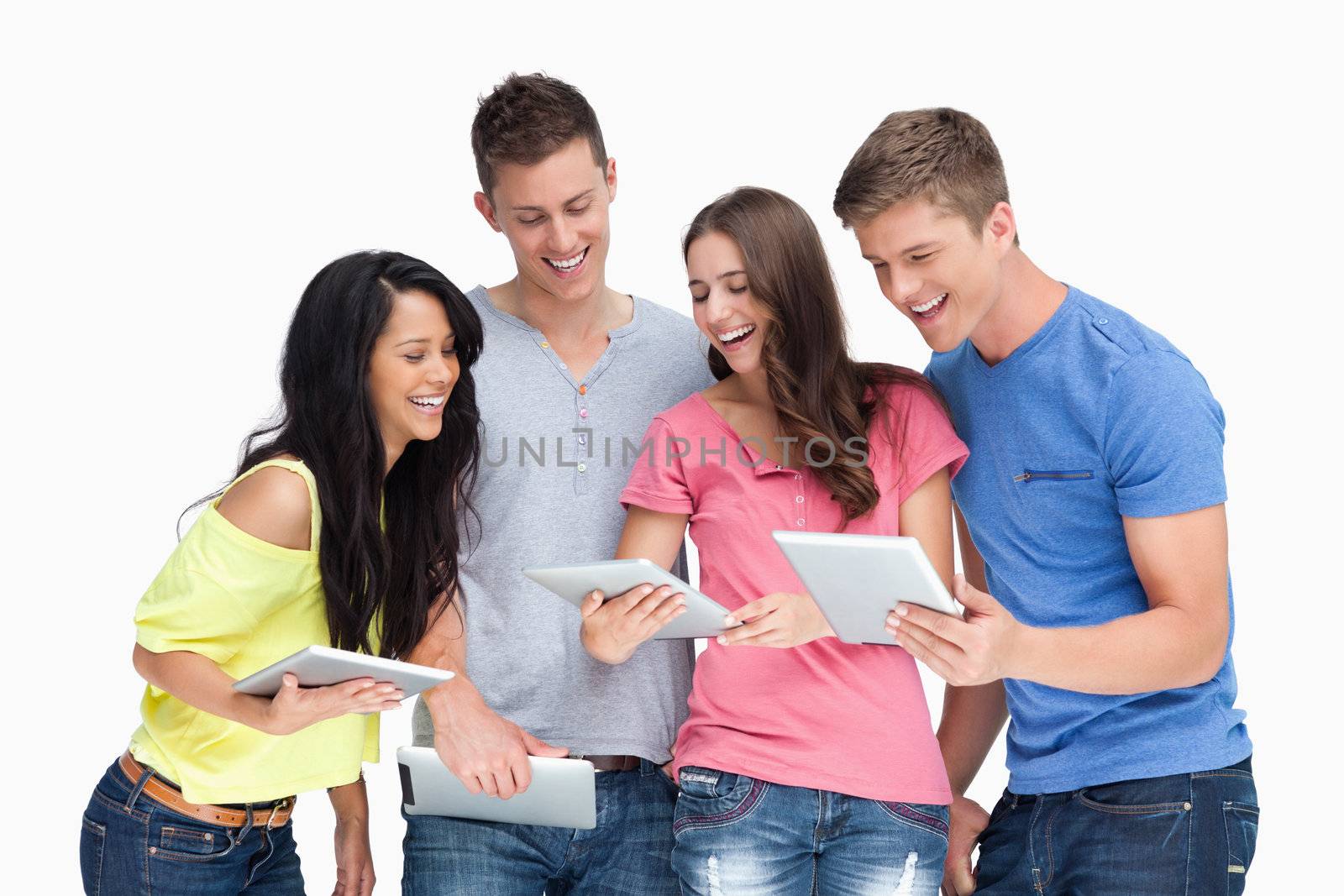 A laughing group of friends looking at their tablets while beside one another