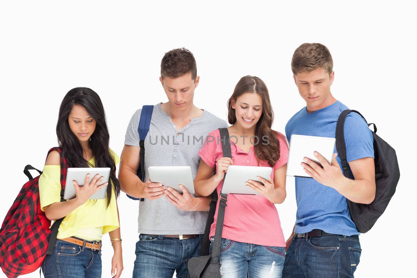 A group of students looking at their tablet pc's with backpacks on