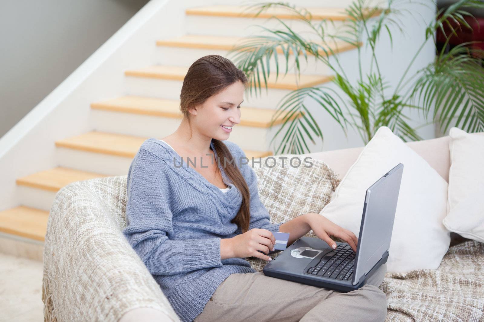 Woman sitting on a sofa while using a notebook by Wavebreakmedia