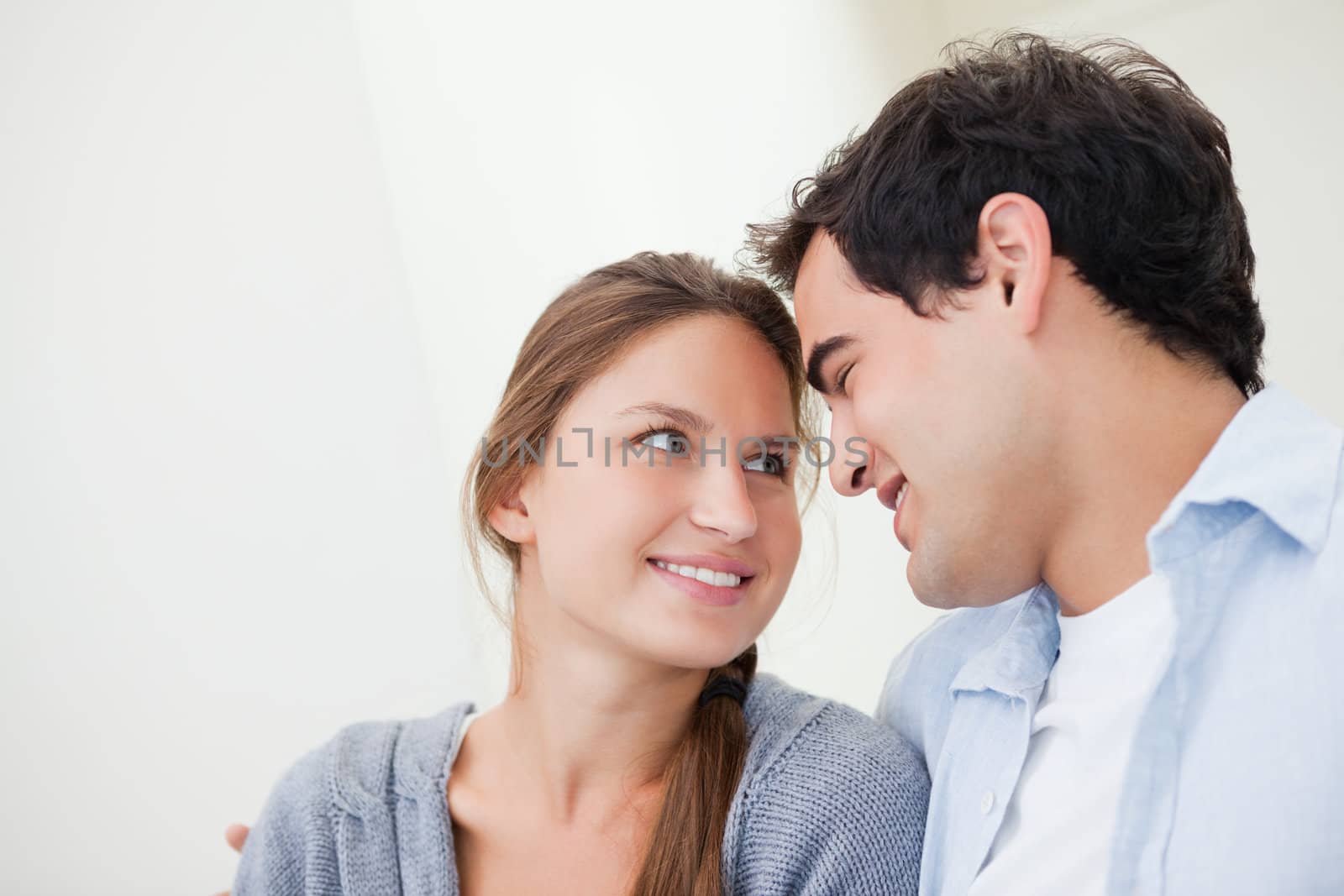 Couple smiling while embracing each other against grey background