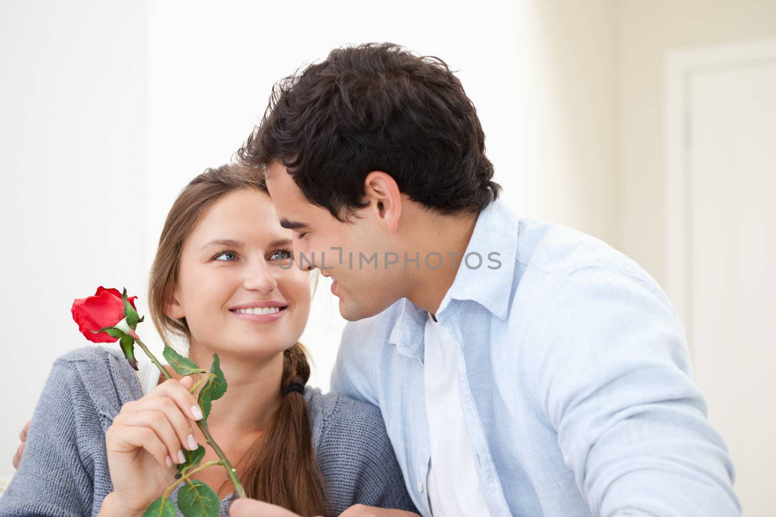 Man offering a rose to a Woman while embracing indoors