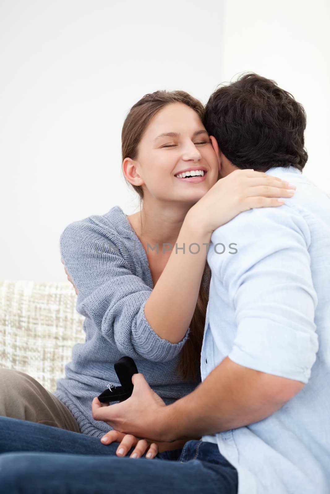 Couple embracing eachother while holding a jewel case against grey background