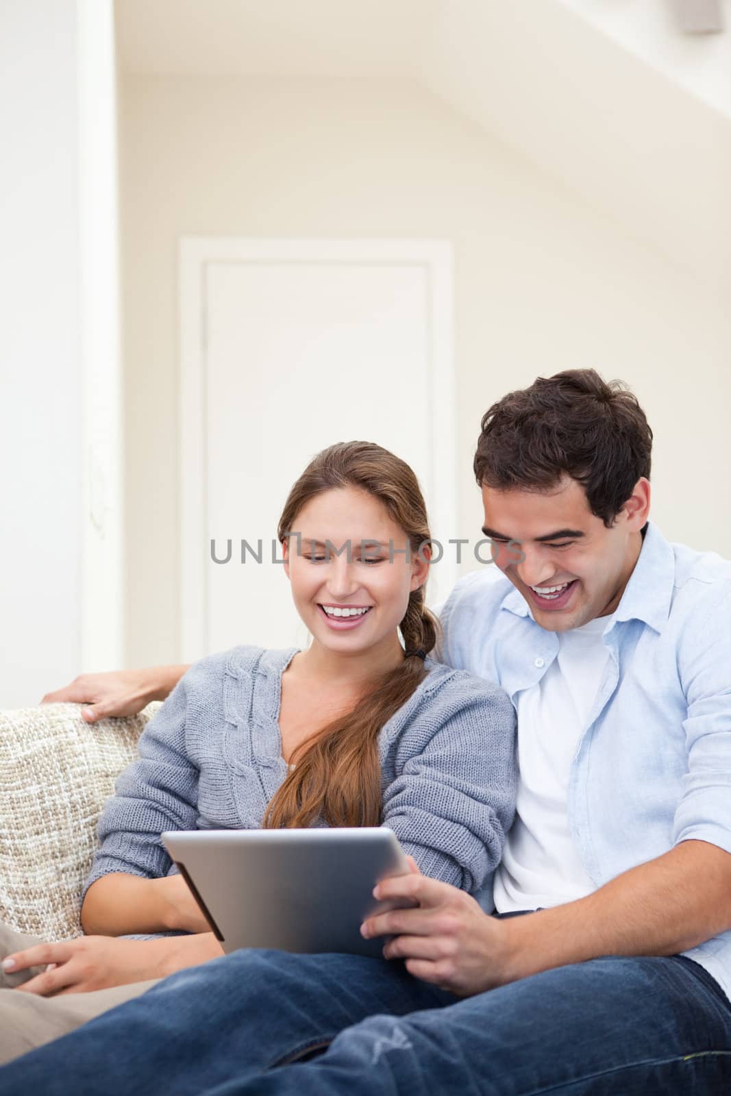 Couple laughing while holding a laptop in a sitting room